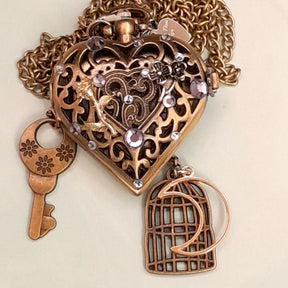 Handmade magical fantasy heart pocket watch necklace with filigree front, lavender Swarovski crystals, flower key and birdcage charms, antiqued brass, Victorian style vintage style
