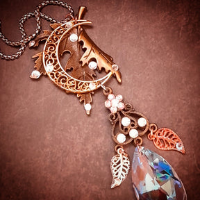 Rachel Flam Design Victorian style and vintage style magical necklace pendant resting in a palm, showing the large Swarovski® crystal teardrop, two dangling leaf charms, and sparkling flower connector.