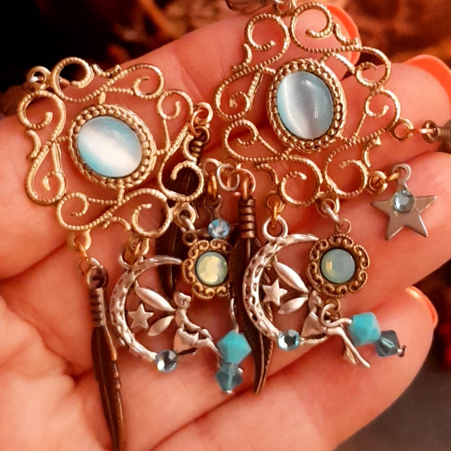Magical Halloween chandelier earrings with oval Cat’s Eye crystals, Pacific Opal and Turquoise Swarovski crystals, crescent moons, stars, fairy-inspired charms, and long feather details, Victorian style vintage style earrings by Rachel Flam Design