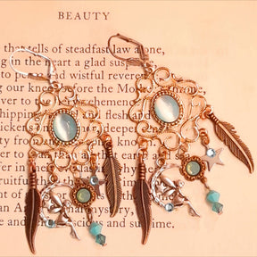 Magical Halloween chandelier earrings featuring glowing oval Cat’s Eye crystals, Pacific Opal and Turquoise Swarovski crystals, fairy-inspired charms, crescent moons, stars, and feather details, Victorian style vintage style jewelry by Rachel Flam Design


