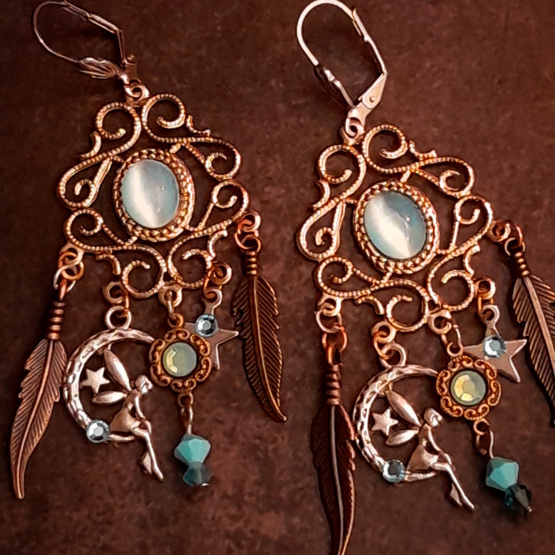 Magical Halloween chandelier earrings with oval Cat’s Eye crystals, Pacific Opal and Turquoise Swarovski crystals, crescent moons, stars, fairy details, and long feather charms, Victorian style vintage style earrings by Rachel Flam Design