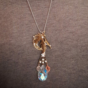 Rachel Flam Design Victorian style and vintage style fantasy statement necklace worn over a gray top, showing the maple leaf, crescent moon, and large Swarovski® crystal teardrop pendant.