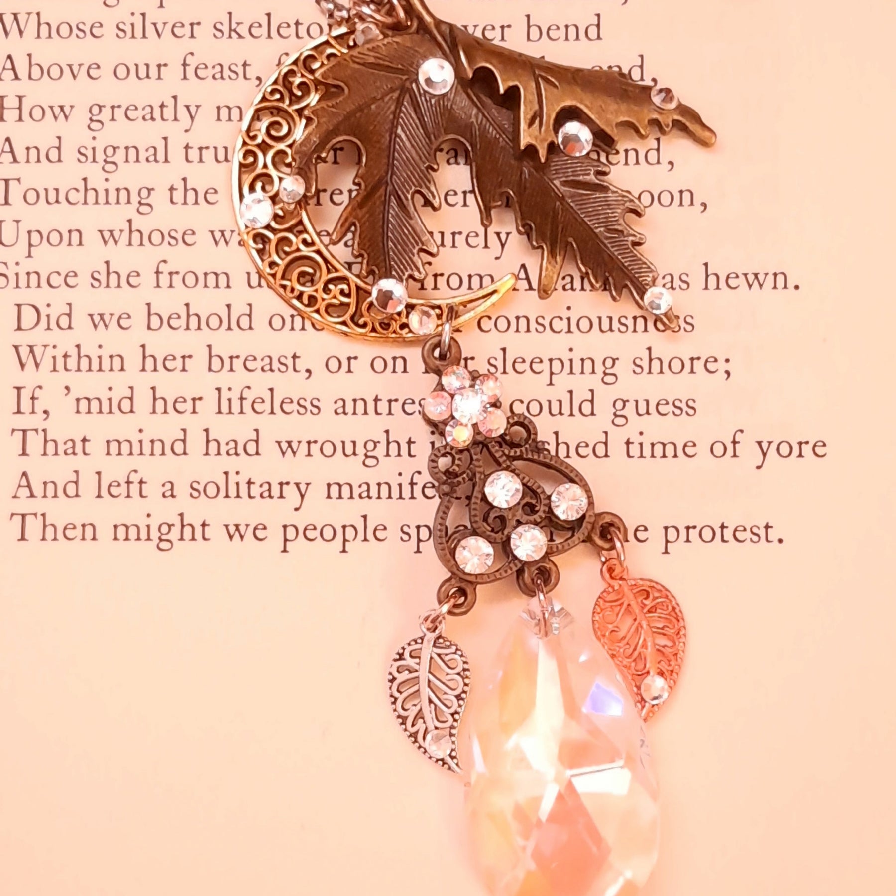 Victorian style and vintage style maple leaf and crescent moon necklace by Rachel Flam Design, created with Swarovski® Crystals, displayed on a poetry page with dangling leaves and a luminous teardrop.
