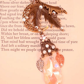 Victorian style and vintage style maple leaf and crescent moon necklace by Rachel Flam Design, created with Swarovski® Crystals, displayed on a poetry page with dangling leaves and a luminous teardrop.