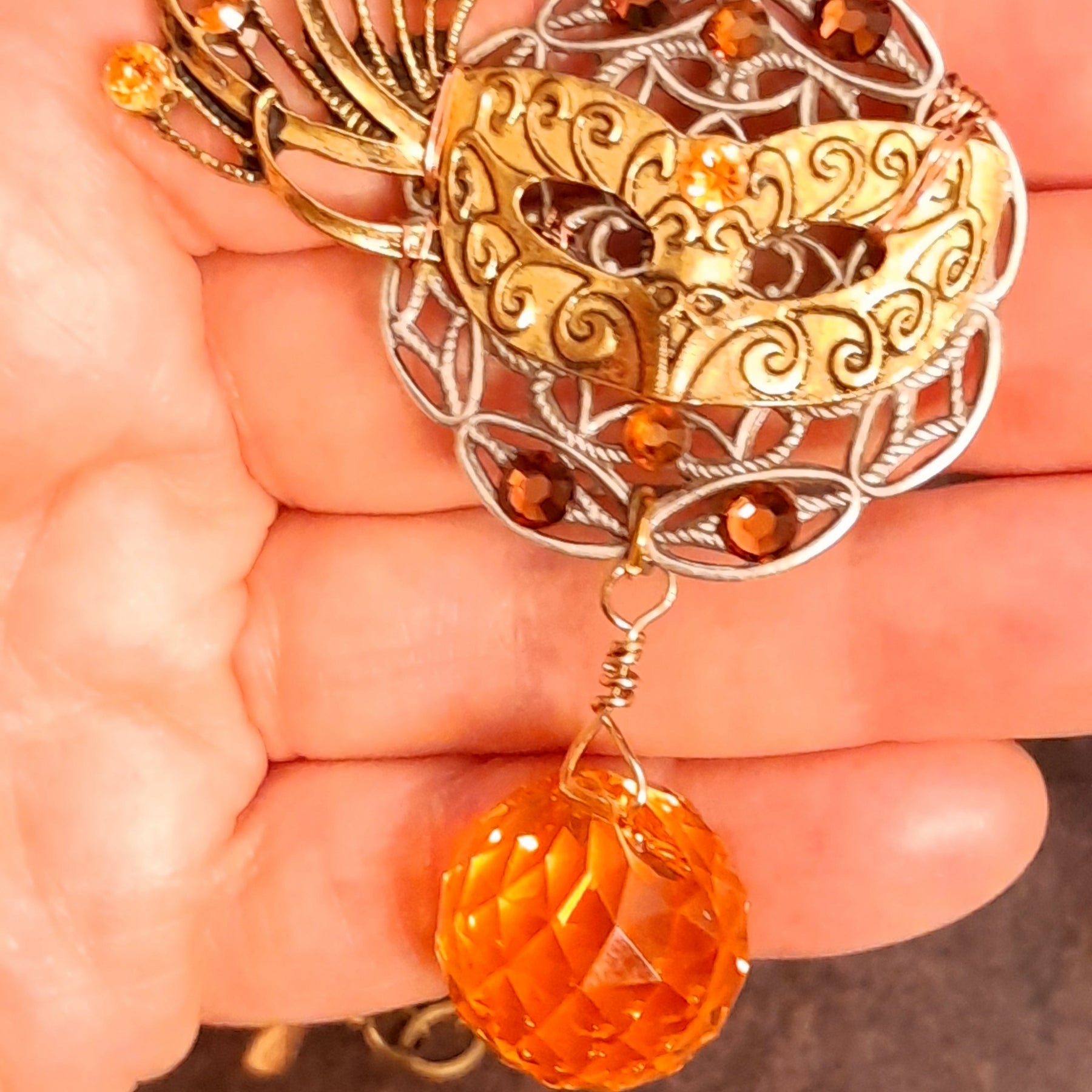 Masquerade necklace decorated with an intricate mask, ornate filigree, fiery orange Swarovski crystals, and a faceted Citrine crystal ball, nature-inspired Halloween jewelry in Victorian style and vintage style by Rachel Flam Design