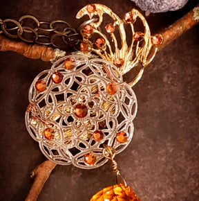 Masquerade mask necklace with detailed circular filigree, warm-toned Swarovski crystals, and a dramatic Citrine crystal ball, magical fantasy Halloween jewelry with Victorian style vintage style detail by Rachel Flam Design