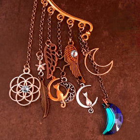 Close up of a Victorian style and vintage style ear wrap by Rachel Flam Design, featuring cats inside crescents, wing and feather charms, Swarovski crystals and a faceted blue moon drop.