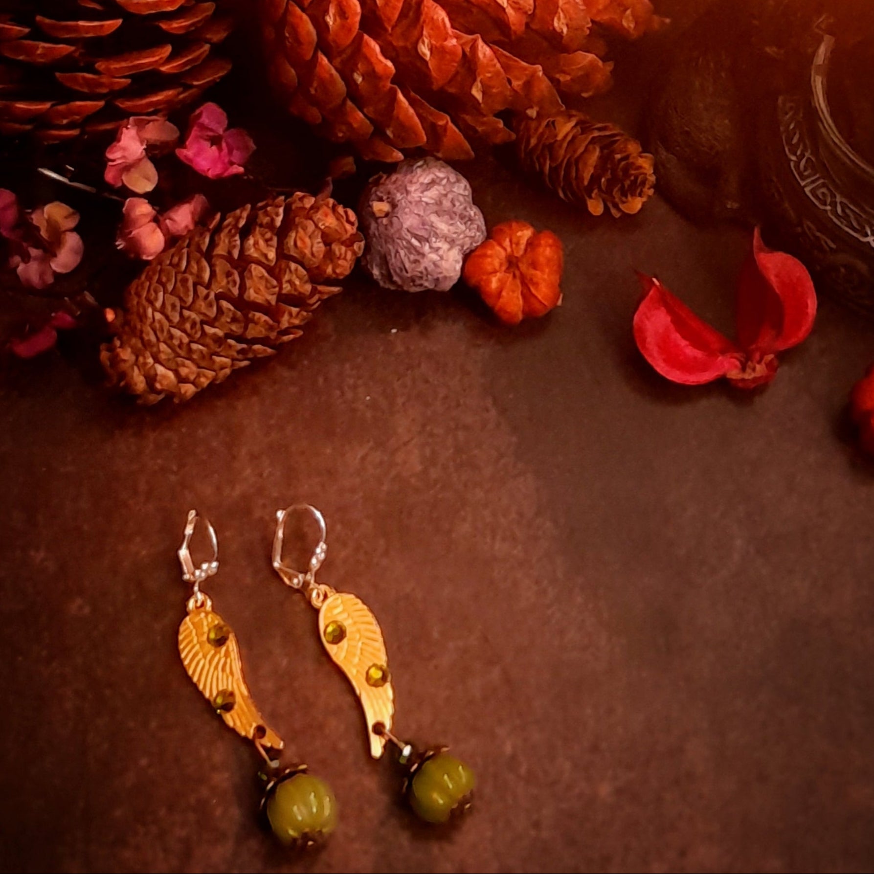 Victorian style vintage style angel wing pumpkin earrings with Swarovski Olivine crystals photographed with pinecones and miniature pumpkins, magical fantasy jewelry by Rachel Flam Design