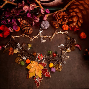 Close-up of handmade Halloween pumpkin necklace details surrounded by maple leaves and colorful Swarovski crystals, Victorian style vintage style nature jewelry


