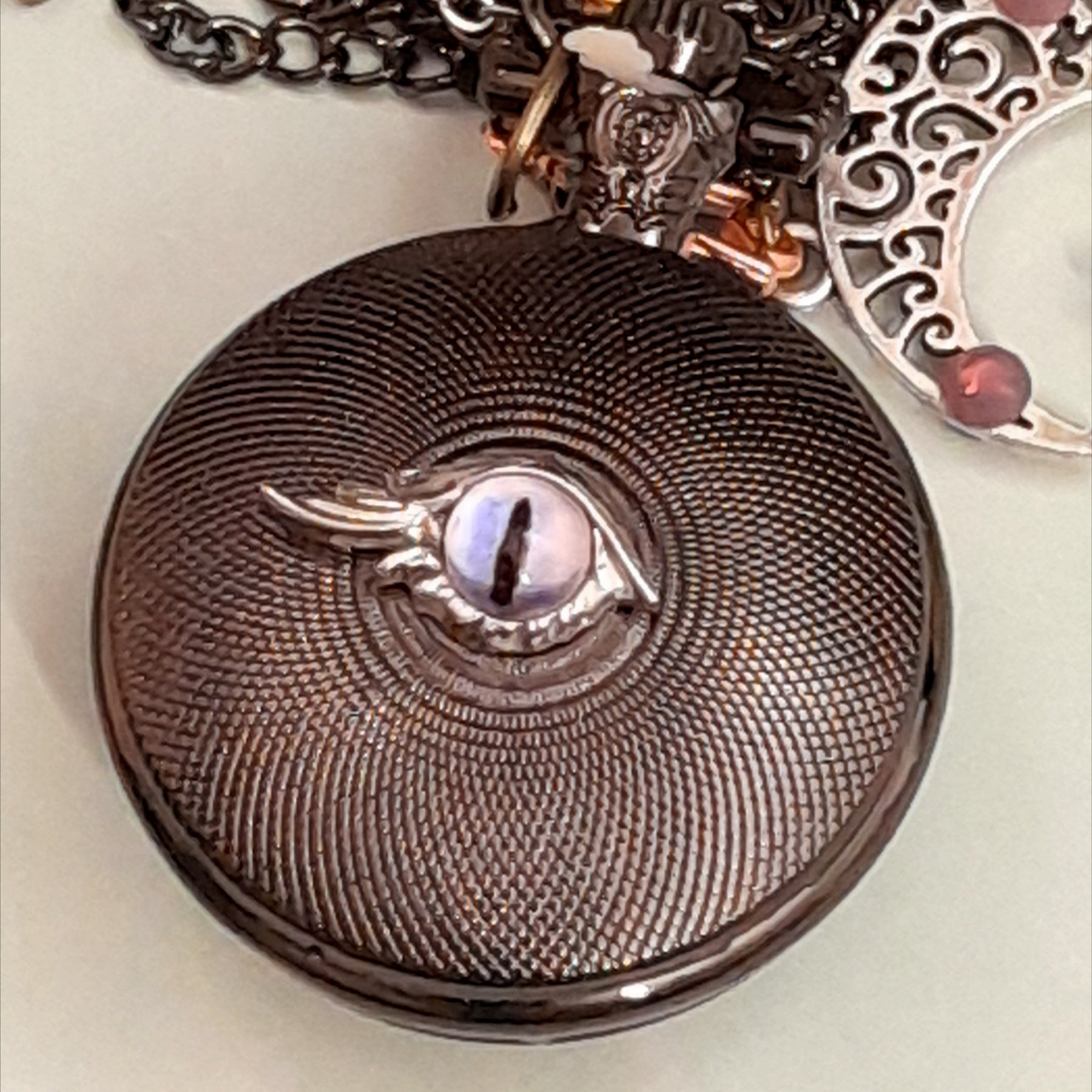 Back of handmade magical fantasy pocket watch necklace showing purple cat eye detail Victorian style vintage style antiqued brass one of a kind