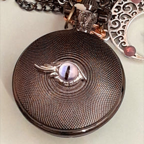 Back of handmade magical fantasy pocket watch necklace showing purple cat eye detail Victorian style vintage style antiqued brass one of a kind