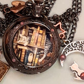 Detail of handmade magical fantasy pocket watch necklace showing cat and books scene with Swarovski purple crystals and antiqued brass chain Victorian style vintage style