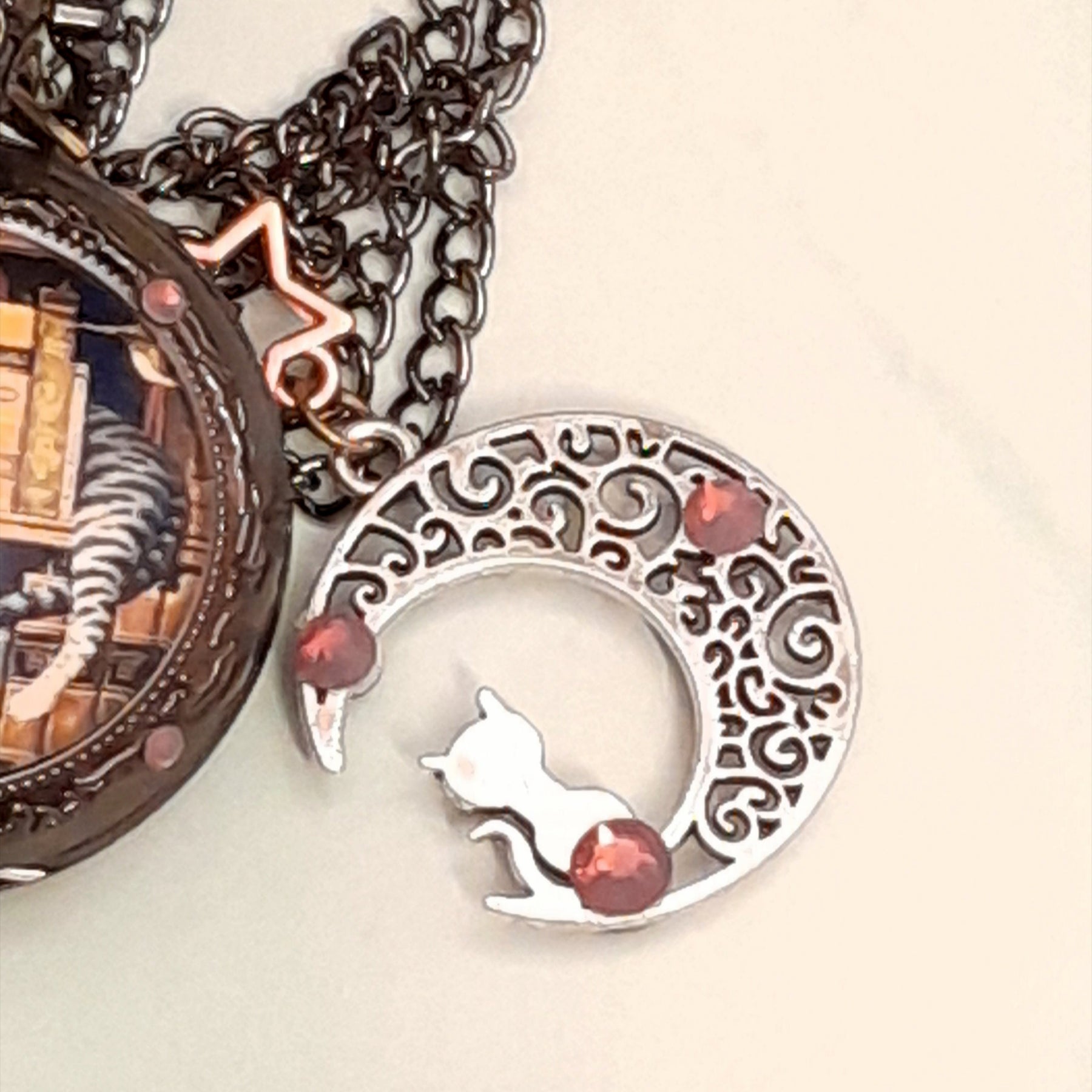 Close up of filigree crescent moon charm with cat silhouette and Swarovski purple crystals on handmade fantasy pocket watch necklace Victorian style vintage style