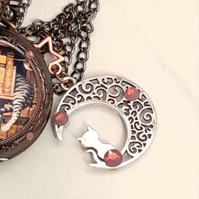 Close up of filigree crescent moon charm with cat silhouette and Swarovski purple crystals on handmade fantasy pocket watch necklace Victorian style vintage style