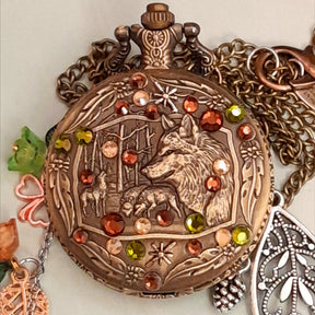 Handmade magical fantasy wolf pocket watch necklace close up with green and brown Swarovski crystals on antiqued brass wolf forest scene, Victorian style vintage style