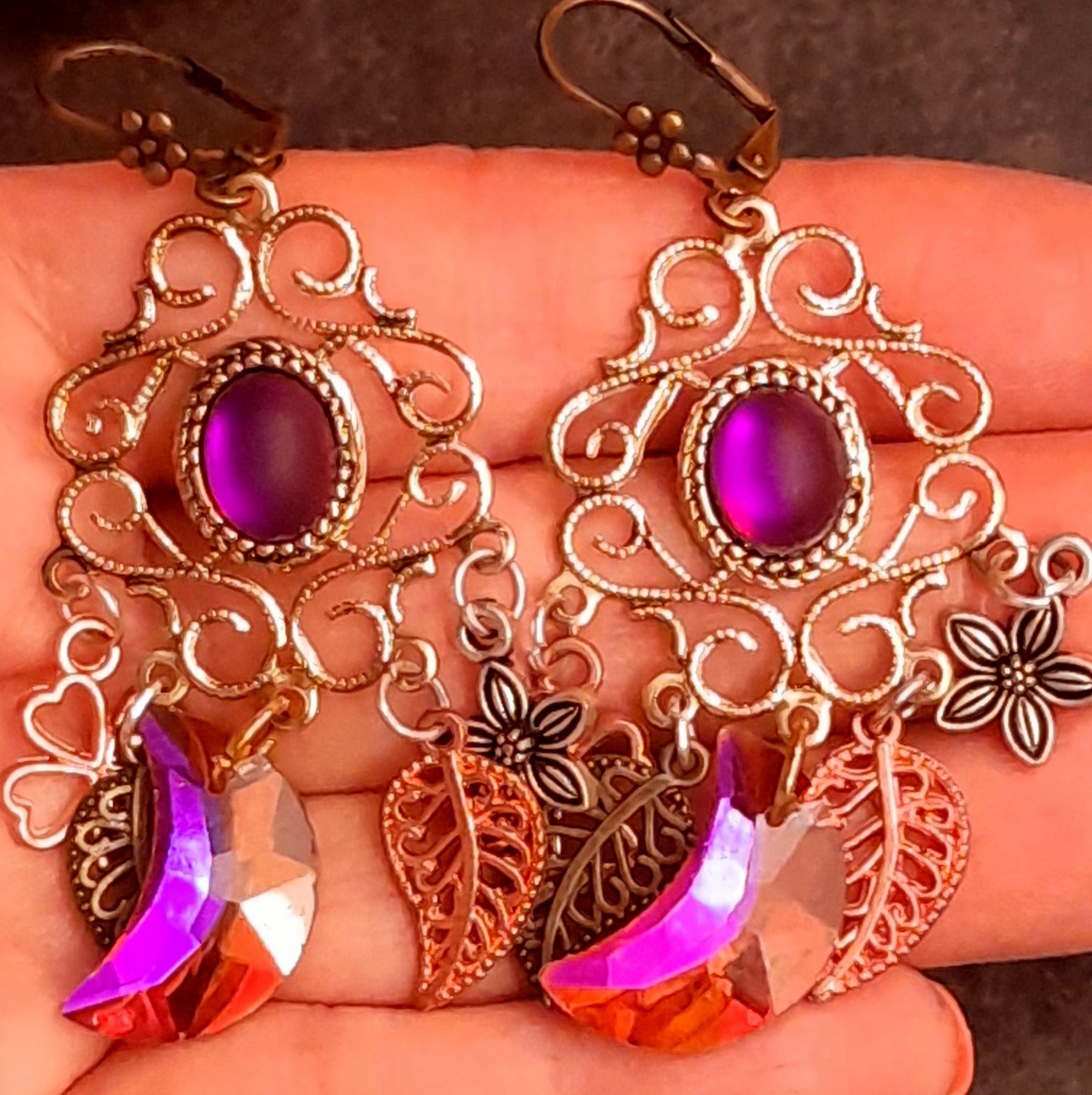Closeup of ornate chandelier earrings with fuchsia Swarovski crescents, oval crystals, flowers, clovers, and leaves in Victorian style and vintage style by Rachel Flam Design