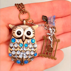 Cute owl pocket watch necklace held in hand showing blue flower fairy bird cage charms Swarovski blue crystals animal jewelry Victorian style vintage style handmade Rachel Flam Design