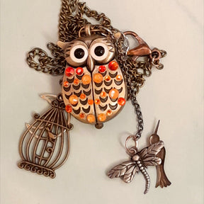 Cute owl pocket watch necklace flat lay full view with birdcage dragonfly hummingbird charms Swarovski orange crystals animal jewelry Victorian style vintage style handmade Rachel Flam Design