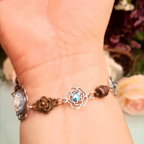 Handmade fantasy bee hand chain slave bracelet  on hand close up of bracelet back showing open rose charm with blue crystal and rose bud charms Victorian style vintage style