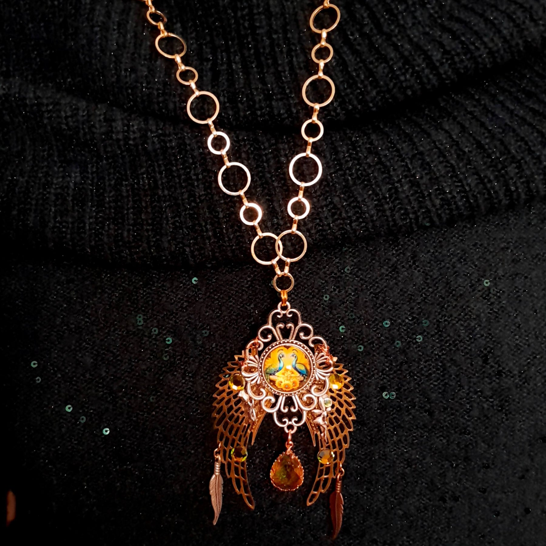 victorian style necklace with a peacock cabochon. Bright golden yellow and green crystals. Feather accents, a fairy, and a striking teardrop crystal