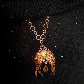 victorian style necklace with a peacock cabochon. Bright golden yellow and green crystals. Feather accents, a fairy, and a striking teardrop crystal