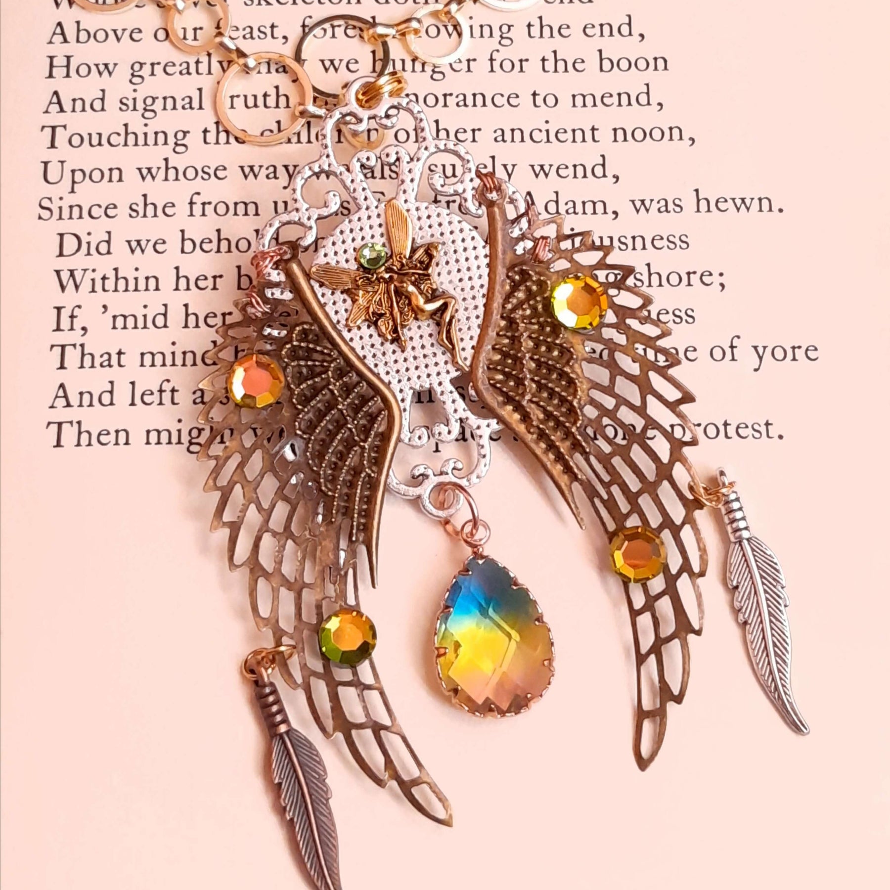 victorian style necklace with a peacock cabochon. Bright golden yellow and green crystals. Feather accents, a fairy, and a striking teardrop crystal