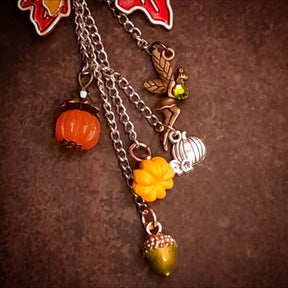 Detail of pumpkin, acorn and winged fairy charms with olivine Swarovski crystal accents hanging from chains, Victorian style vintage style nature brooch by Rachel Flam Design