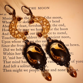 Crow and star moon dangle earrings resting on a vintage moon poem page, Victorian style Swarovski crystal nature Halloween earrings, Rachel Flam Design
