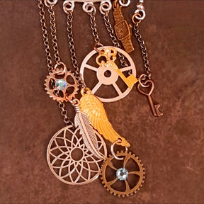 Close-up of a Rachel Flam Design steampunk ear wrap and ear cuff with light blue Swarovski® crystals on gears, dangling keys, a wing, feather, and watch charm, showing Victorian style and vintage style details.