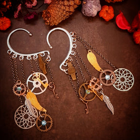 Rachel Flam Design steampunk ear wraps and ear cuffs with light blue Swarovski® crystals, gears, keys, wings, and feathers, combining Victorian style and vintage style on a dark background.