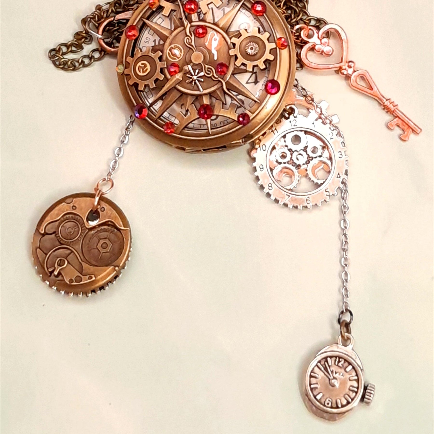 Steampunk pocket watch necklace showing all charms including steampunk gears watch movement disc skeleton key and mini quartz watch charm antiqued brass Victorian style vintage style fantasy handmade
