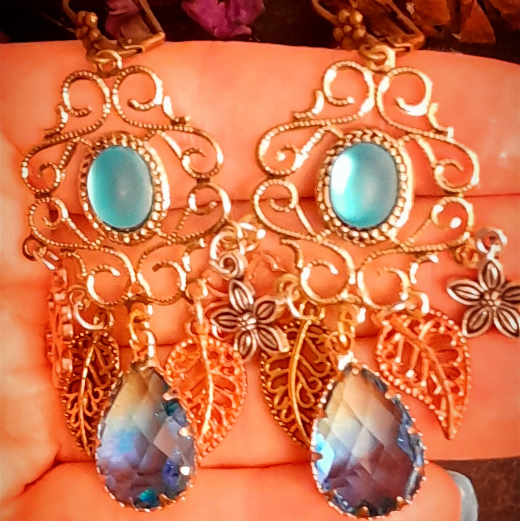 Victorian style and vintage style floral chandelier earrings with luminous turquoise cat eye cabochons, swirling filigree, layered flowers, leafy charms, and dangling glass drops by Rachel Flam Design