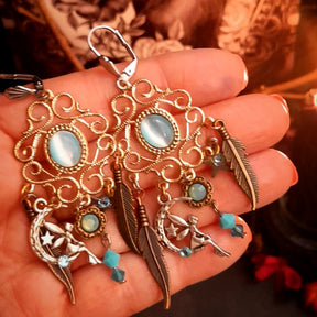 Victorian style magical Halloween chandelier earrings with luminous oval Cat’s Eye crystals, Pacific Opal and Turquoise Swarovski crystals, crescent moons, stars, delicate fairy charms, and long feather accents, vintage style earrings by Rachel Flam Design