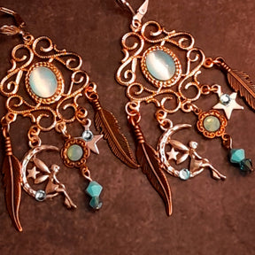 Vintage style magical Halloween chandelier earrings decorated with oval Cat’s Eye crystals, Pacific Opal and Turquoise Swarovski crystals, crescent moons, stars, fairy details, and dramatic feather charms, Victorian style jewelry by Rachel Flam Design