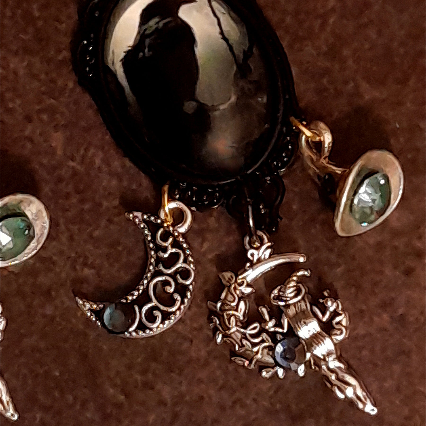 Close-up of handmade witchy earrings showing smoky crystal details, an openwork crescent moon, crystal-set witch hat, and detailed witch charm, Victorian style and vintage style magical fantasy jewelry by Rachel Flam Design