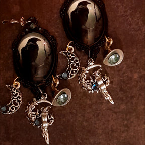 Witchy crow earrings with raven moon cabochons, openwork crescent moons, witch hat details, celestial branches, and smoky Swarovski crystals, Victorian style and vintage style magical fantasy jewelry by Rachel Flam Design