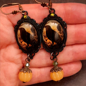 Handmade magical crow earrings with ornate oval frames, yellow crystal accents, pumpkin charms, and a darker woodland feel, Victorian style and vintage style fantasy jewelry by Rachel Flam Design