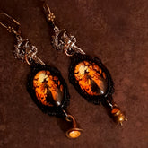 Handmade witchy fairy earrings with glowing orange Swarovski crystals, moonlit witch scenes, celestial stars, broom, and hidden fairy details, Victorian style and vintage style magical fantasy jewelry by Rachel Flam Design