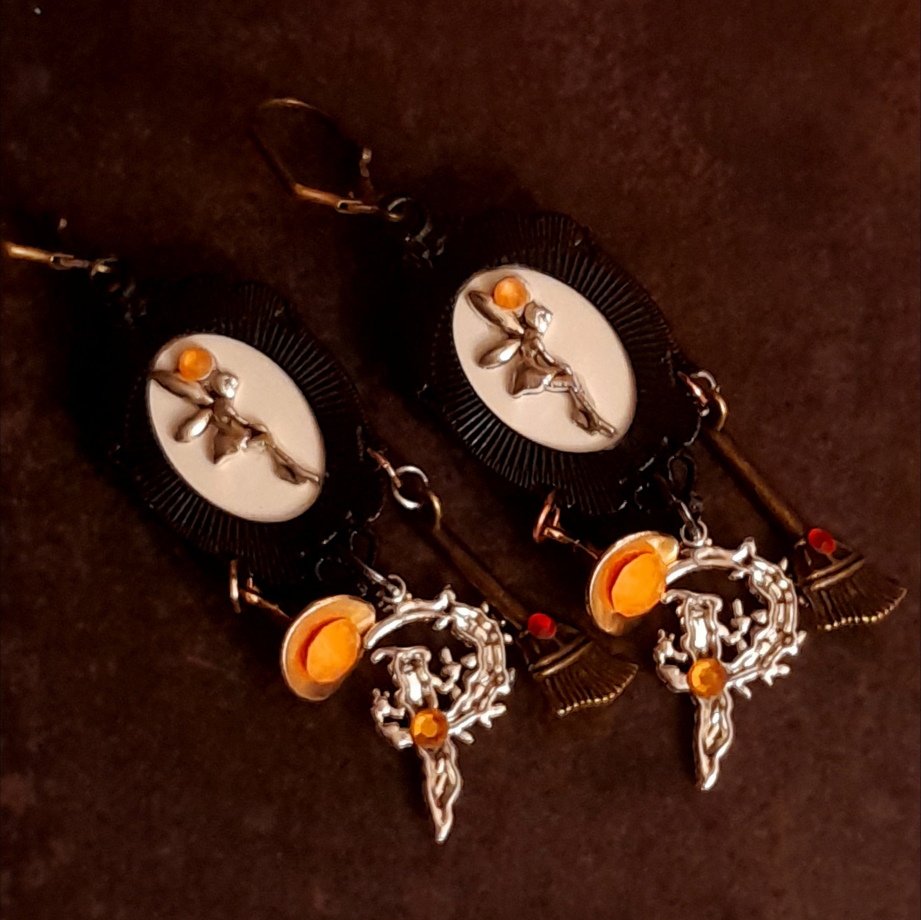 Reverse view of handmade witchy fairy earrings showing hidden fairies on the backs of the focal pieces, orange Swarovski crystals, broom and witch hat dangles, Victorian style and vintage style magical fantasy jewelry by Rachel Flam Design