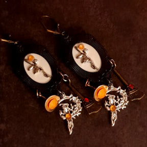 Reverse view of handmade witchy fairy earrings showing hidden fairies on the backs of the focal pieces, orange Swarovski crystals, broom and witch hat dangles, Victorian style and vintage style magical fantasy jewelry by Rachel Flam Design