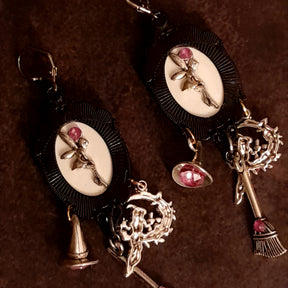 Reverse view of handmade witchy fairy earrings showing hidden fairy charms on the backs, pink Swarovski crystals, witch hat and broom dangles, Victorian style and vintage style magical fantasy jewelry by Rachel Flam Design