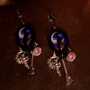 Detailed witchy moon earrings with moonlit witch cabochons, purple-blue scenes, pink Swarovski crystals, crystal-filled witch hat, and long broom dangles, Victorian style and vintage style fantasy jewelry by Rachel Flam Design