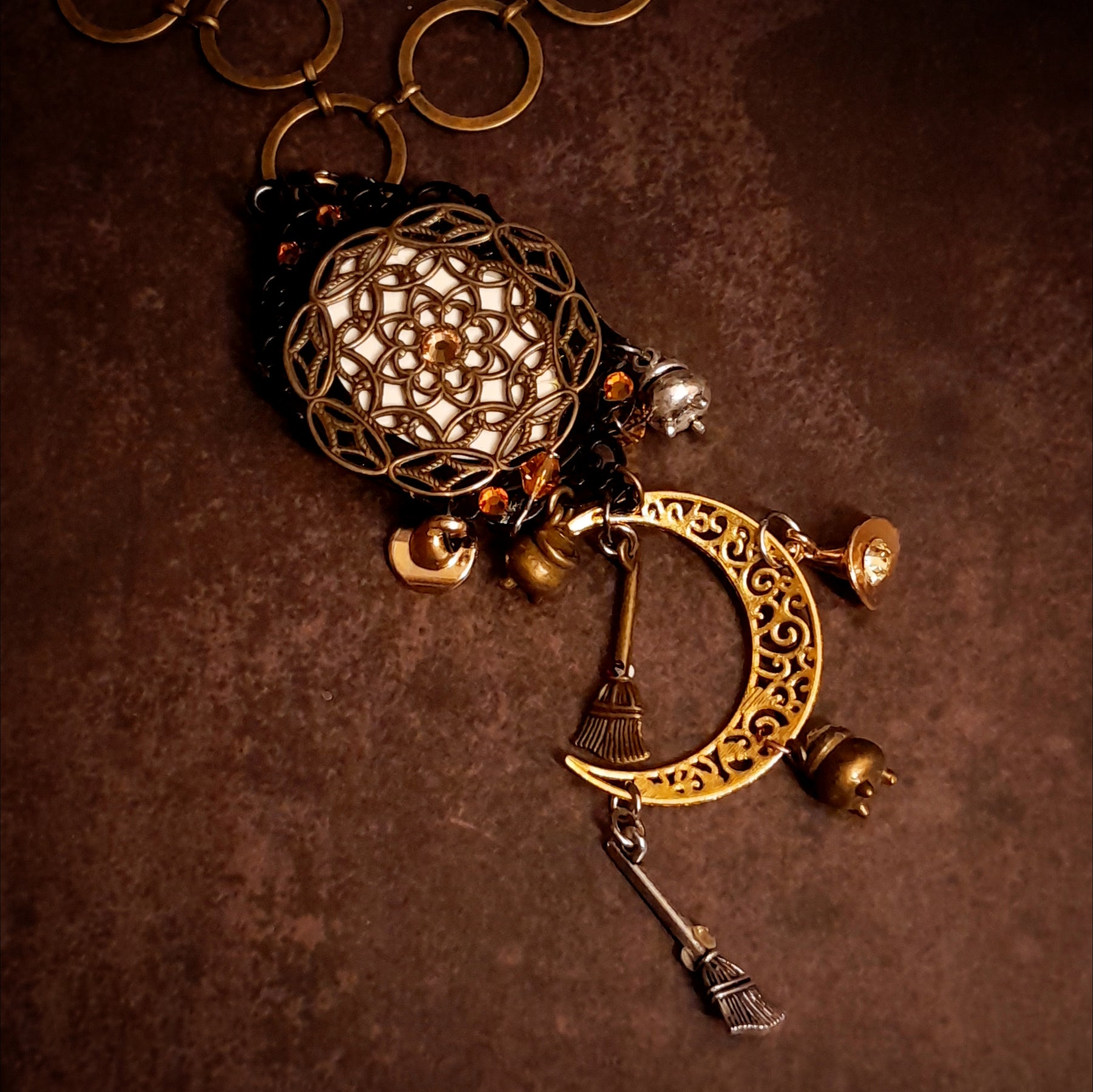 Magical fantasy crescent moon necklace decorated with witchy charms, broomsticks, raven details, potion vessels, dragonfly, and Swarovski crystals, Victorian style and vintage style jewelry by Rachel Flam Design