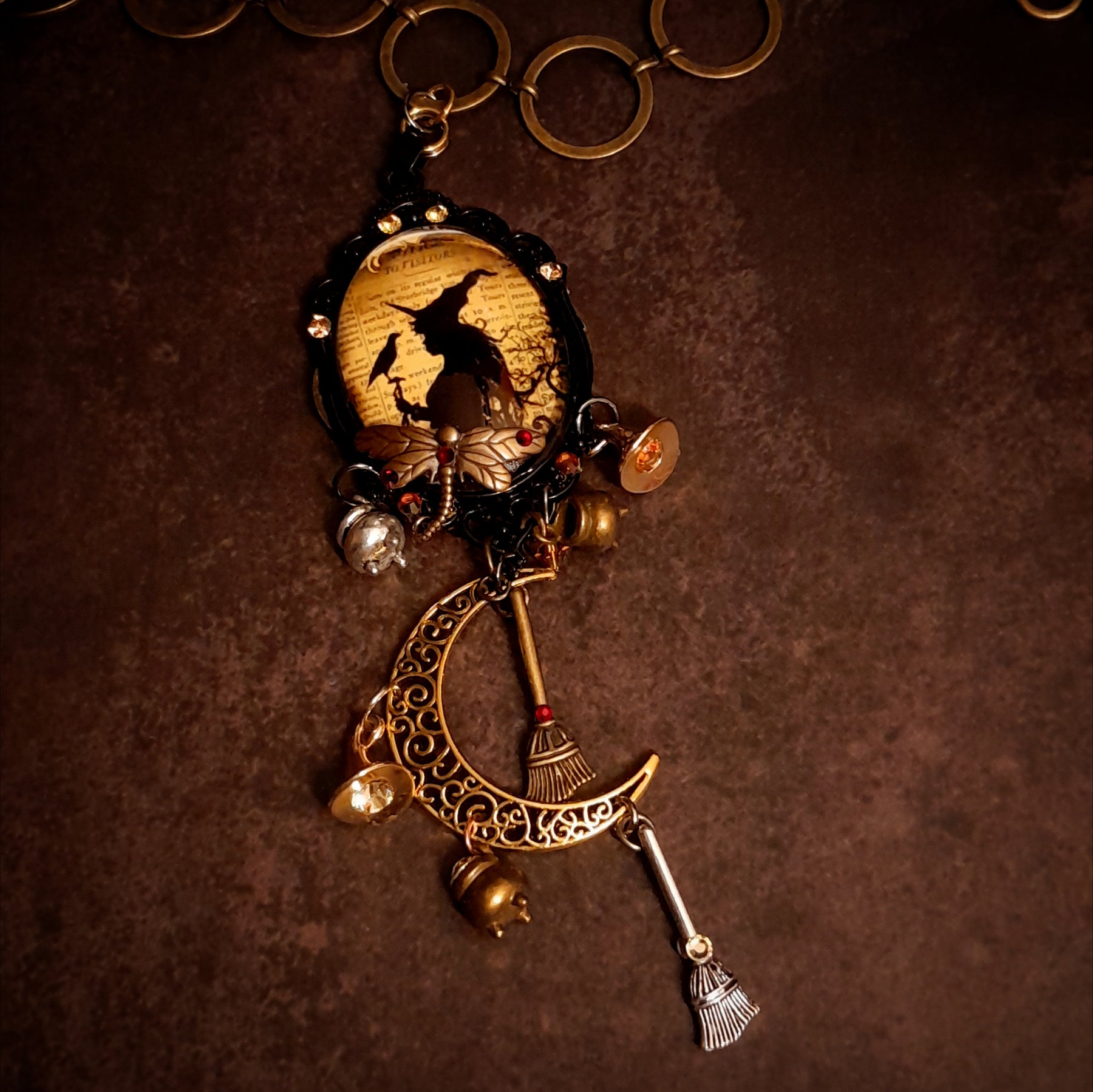 Detailed witchy crescent moon necklace with raven symbolism, broomsticks, potions, witch hat charms, dragonfly detail, and Swarovski crystals, Victorian style and vintage style fantasy jewelry by Rachel Flam Design
