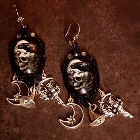 Handmade witchy raven and skull earrings with pale moon imagery, smoky Swarovski crystals, crescent moon charms, witch figures, and celestial details, Victorian style and vintage style magical fantasy jewelry by Rachel Flam Design