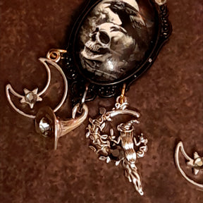 Close-up of witchy raven and skull earrings showing the macabre focal artwork, smoky Swarovski crystals, crescent moon with star detail, and crystal-set witch hat charm, Victorian style and vintage style magical fantasy jewelry by Rachel Flam Design