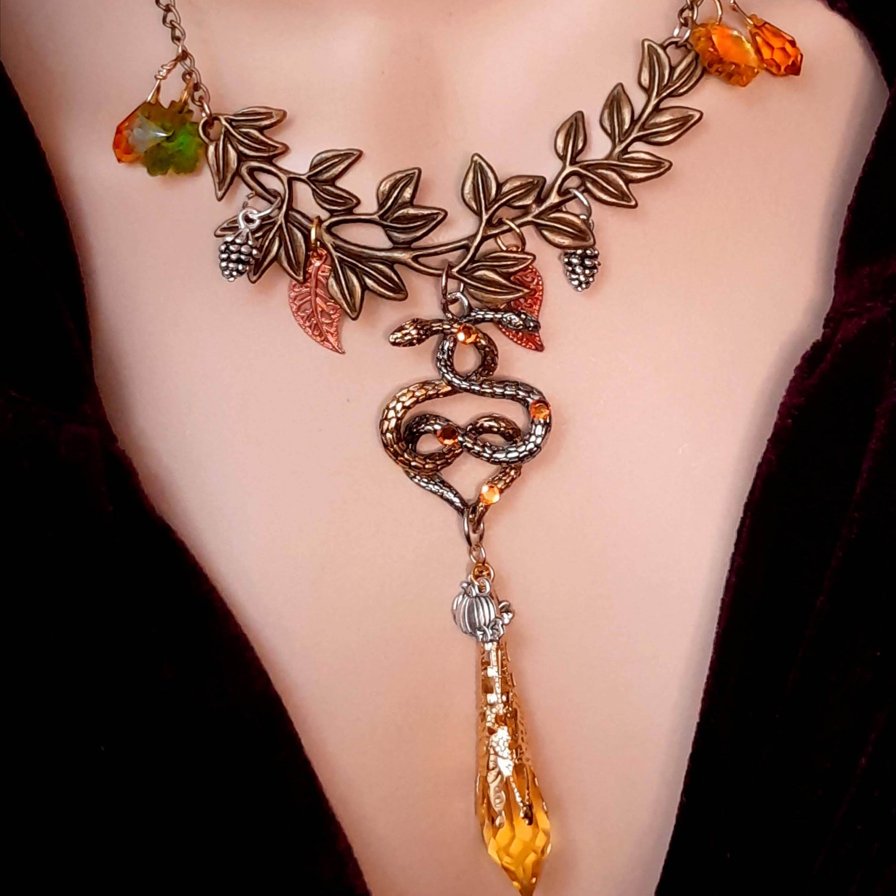 swarovski crystal necklace with large yellow icicle crystal and flower crystals in green and orange. Autumn necklace with nature motifs pinecone leaves and 2 intertwined snakes