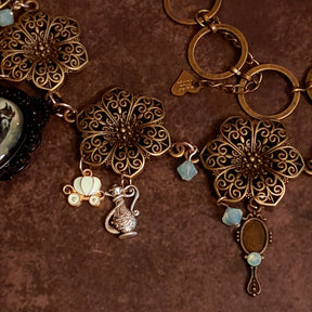 Detail of layered charm cluster surrounding the black crow cabochon, Pumpkin carriage magical genie lamp magical hand mirror, Victorian style vintage style Swarovski crystal necklace, Rachel Flam Design