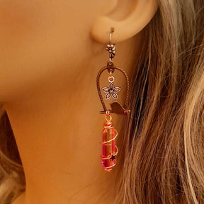 bird earrings with dangling flower and glass drops that change color from yellow to pink. wire wrapped with a moon and star