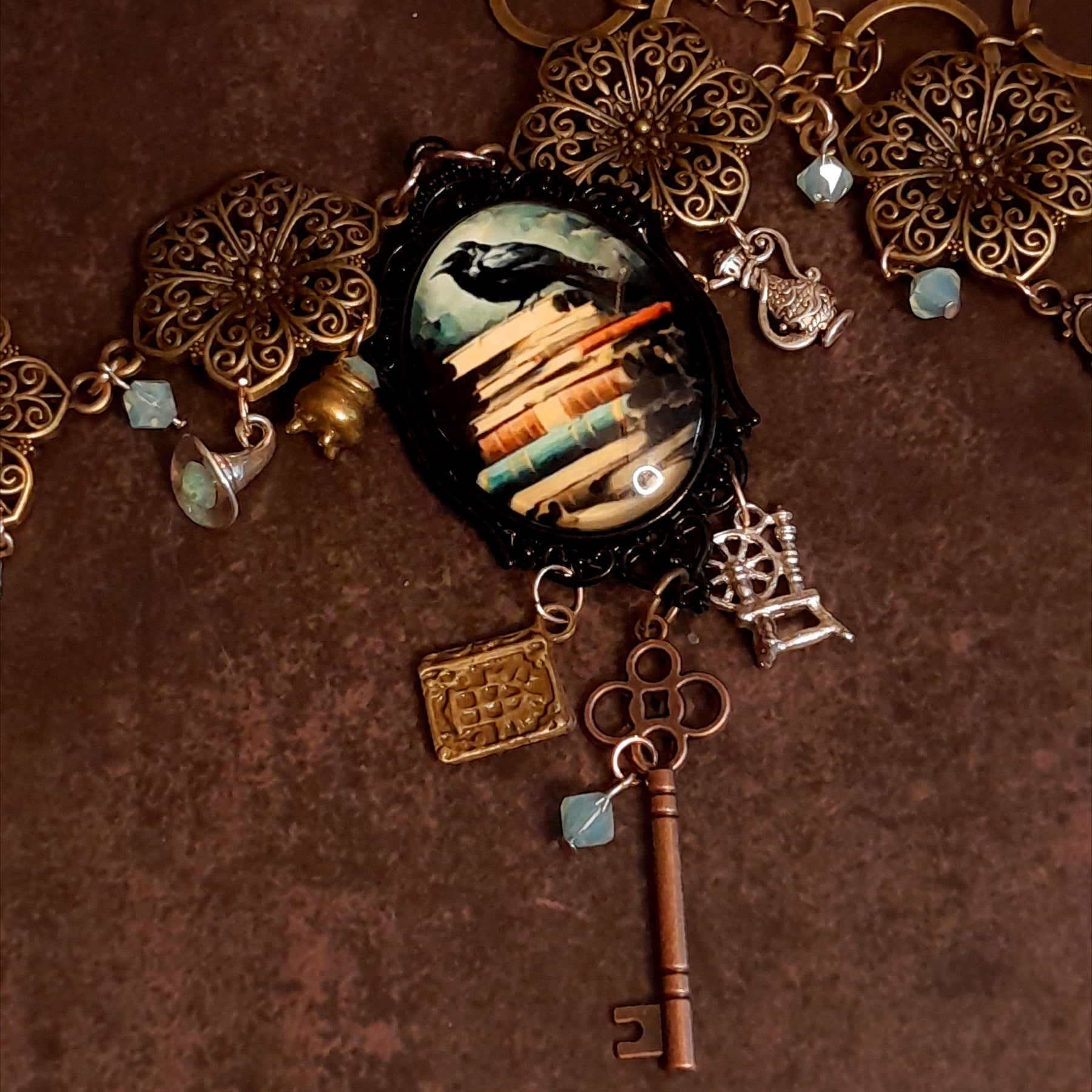 Side angle of black crow fairy tale necklace with witchy charms and Swarovski crystals, Fairy tale book charm Spinning wheel Ornate skeleton key,  Victorian style vintage style jewelry by Rachel Flam Design